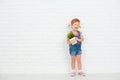 Happy child girl laughing and holding pot with potted plant near