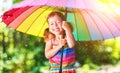 Happy child girl laughs and plays under summer rain with an umbrella Royalty Free Stock Photo