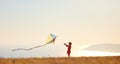 Happy child girl launches a kite at sunset outdoors