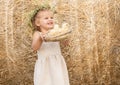 Happy child girl in linen dress smiling with fluffy baby chicks in nest on hay.