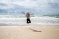 Happy child girl makes a jump on the beach close to the sea