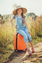 Happy child girl with orange suitcase traveling alone on summer vacation. Kid going to summer camp. Royalty Free Stock Photo