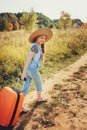 Happy child girl with orange suitcase traveling alone on summer vacation. Kid going to summer camp. Royalty Free Stock Photo