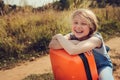 Happy child girl with orange suitcase traveling alone on summer vacation. Kid going to summer camp.