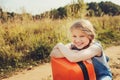 Happy child girl with orange suitcase traveling alone on summer vacation. Kid going to summer camp.