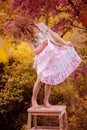 Happy child girl in pink dress playing outdoor in spring garden near blooming crabapple tree Royalty Free Stock Photo