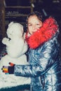 Happy child girl plaing with a snowman on a snowy winter walk.A teenage girl sculpts a snowman Royalty Free Stock Photo