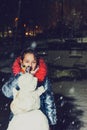 Happy child girl plaing with a snowman on a snowy winter walk.A teenage girl sculpts a snowman