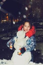 Happy child girl plaing with a snowman on a snowy winter walk.A teenage girl sculpts a snowman