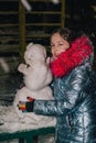 Happy child girl plaing with a snowman on a snowy winter walk.A teenage girl sculpts a snowman