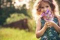 Happy child girl playing with bouquet of bluebells in summer. Royalty Free Stock Photo