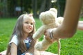 Happy child girl playing with her teddy bear toy sitting on green grass in summer park Royalty Free Stock Photo