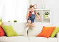 Happy child girl playing and jumping on couch at home Royalty Free Stock Photo