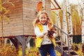 Happy child girl playing little gardener in autumn and picking leaves into basket