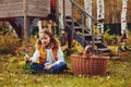 Happy child girl playing little gardener in autumn and picking leaves into basket