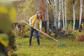 Happy child girl playing little gardener in autumn and picking leaves into basket. Seasonal garden work Royalty Free Stock Photo