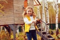 Happy child girl playing little gardener in autumn and picking leaves into basket. Seasonal garden work. Royalty Free Stock Photo