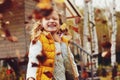 Happy child girl playing little gardener in autumn and picking leaves into basket. Seasonal garden work.