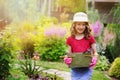 Happy child girl playing little gardener and helping in summer garden, wearing hat and gloves Royalty Free Stock Photo