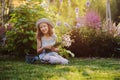 Happy child girl playing little gardener in summer, wearing funny hat and holding bouquet of flowers Royalty Free Stock Photo