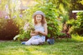 happy child girl playing little gardener in summer, wearing funny hat and holding bouquet of flowers Royalty Free Stock Photo