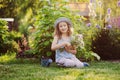happy child girl playing little gardener in summer, wearing funny hat and holding bouquet of flowers. Royalty Free Stock Photo