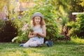 Happy child girl playing little gardener in summer, wearing funny hat and holding bouquet Royalty Free Stock Photo