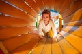 Happy child girl playing in tunnel on playground