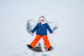 Happy child girl playing on a winter walk in nature. Kid making snow angel. Happy preschool girl having fun on snowing Royalty Free Stock Photo