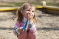 Happy child girl plays with toys in a sandbox, smile, cover your mouth with your hand