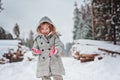 Happy child girl plays in winter snowy forest with tree felling on background Royalty Free Stock Photo