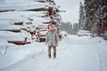 Happy child girl plays on winter snowy road with tree felling on background Royalty Free Stock Photo