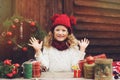 Happy child girl in red hat and scarf wrapping Christmas gifts at cozy country house, decorated for New Year and Christmas Royalty Free Stock Photo