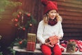 Happy child girl in red hat and scarf wrapping Christmas gifts at cozy country house, decorated for New Year and Christmas Royalty Free Stock Photo