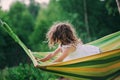 Happy child girl relaxing in hammock on summer camp in forest. Outdoor seasonal activities Royalty Free Stock Photo