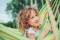Happy child girl relaxing in hammock on summer camp in forest. Outdoor seasonal activities Royalty Free Stock Photo