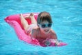 Happy child girl relaxing on inflatable air mattress in swimming pool on sunny summer day during tropical vacations Royalty Free Stock Photo