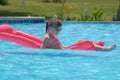 Happy child girl relaxing on inflatable air mattress in swimming pool on sunny summer day during tropical vacations Royalty Free Stock Photo