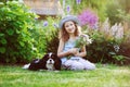 Happy child girl relaxing in summer garden with her spaniel dog, wearing gardener hat and holding bouquet of flowers Royalty Free Stock Photo