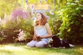 happy child girl relaxing in summer garden with her spaniel dog, wearing gardener hat and holding bouquet Royalty Free Stock Photo