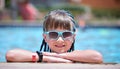 Happy child girl relaxing on swimming pool side on sunny summer day