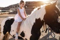 Happy child girl riding a horse at summer sunset - Main focus on kid face