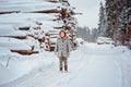 Happy child girl on the road in winter snowy forest with tree felling on background