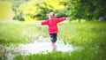 Happy child girl running and jumping in puddles after rain Royalty Free Stock Photo