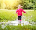 Happy child girl running and jumping in puddles after rain Royalty Free Stock Photo