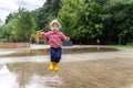 happy child girl running and jumping in puddles after rain in summer Royalty Free Stock Photo