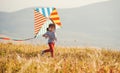 Happy child girl running with kite at sunset outdoors