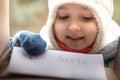 Happy child girl sends a letter to Santa Claus to North Pole at mail box as seen from the inside Royalty Free Stock Photo