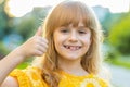 Happy child girl showing thumbs up, like ok yes sign good positive feedback victory win in city park Royalty Free Stock Photo