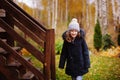 Happy child girl standing by wooden house stairs in late autumn garden